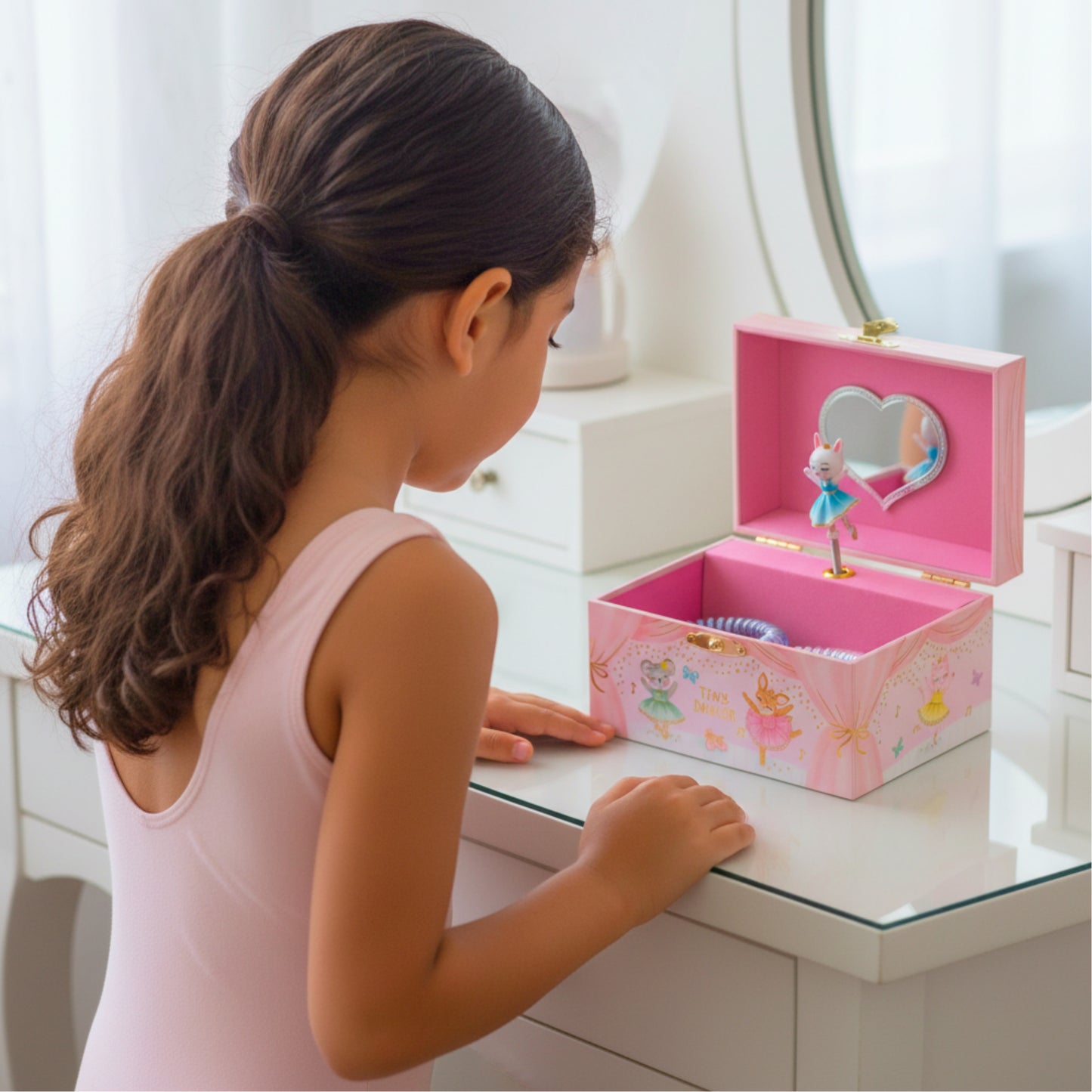 Young girl playing with a pink music box featuring fairy designs.