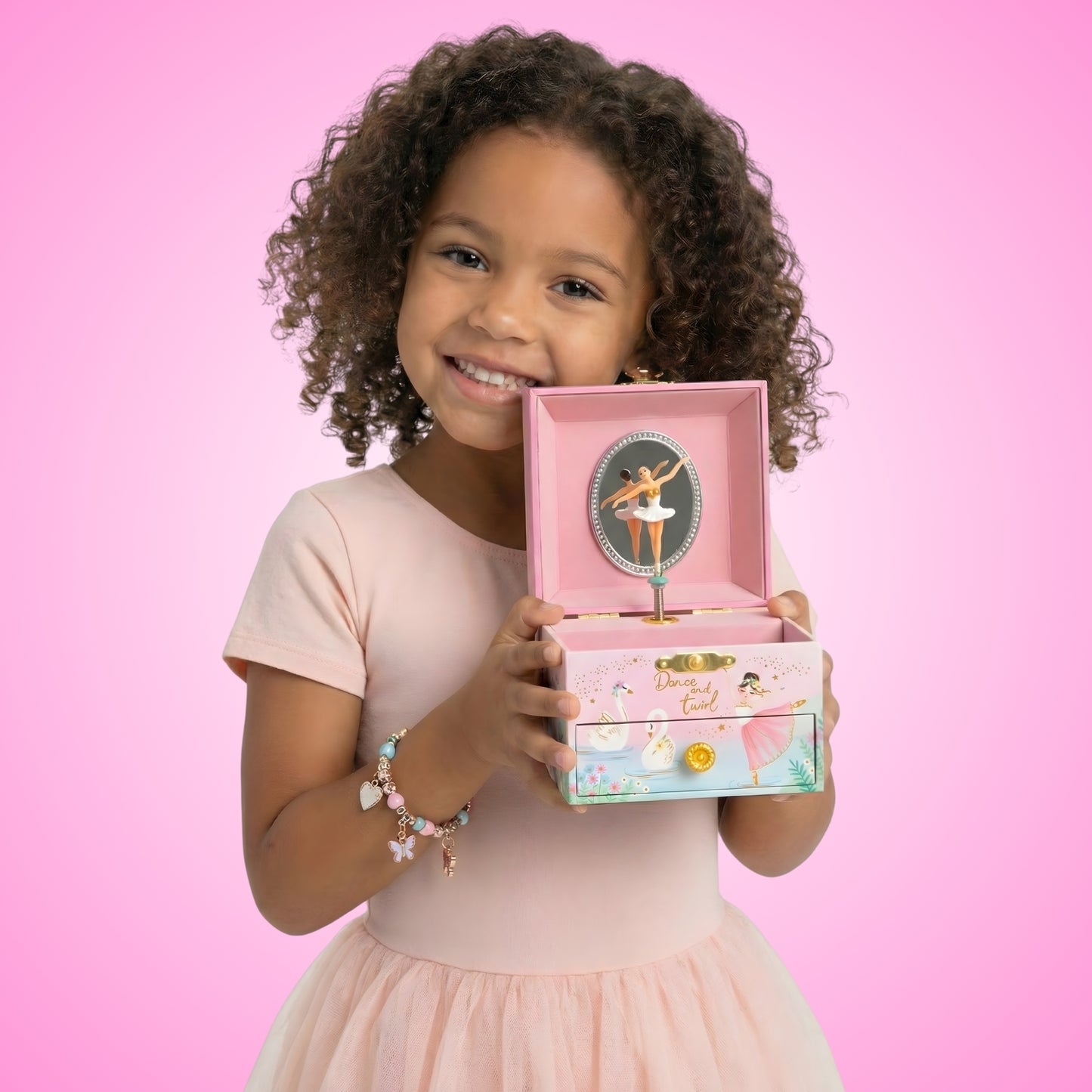 little girl holding a pink ballerina musical jewelry box that plays swan lake tune