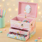 Pink jewelry box with ballerina design on a wooden surface with colorful pencils and beads.