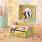 Music box with horse design on a wooden surface with colorful pencils and flowers.