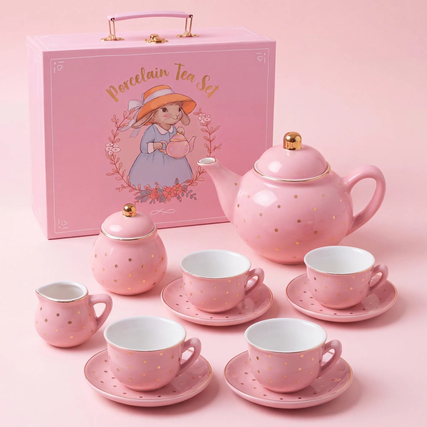 Pink and gold polka dot porcelain tea set for girls with teapot, sugar bowl, milk pot, 4 cups and saucers beside a pink carry case